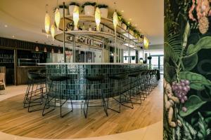 a bar with black stools in a restaurant at Live Hotels Bordeaux Lac in Bordeaux