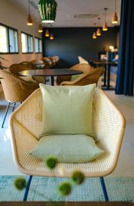 a wicker chair with a pillow in a room at Live Hotels Bordeaux Lac in Bordeaux