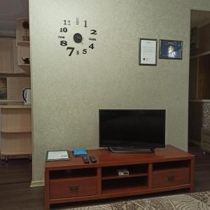 ein Wohnzimmer mit einem TV und einer Uhr an der Wand in der Unterkunft Apartments on 23,1 Nаzarbaeva Ave in Öskemen