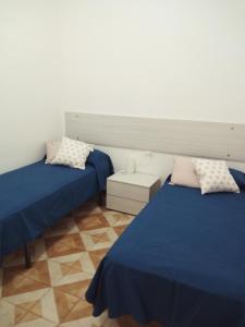 twee bedden in een kamer met blauwe lakens en kussens bij Appartamento a Mondello in Mondello