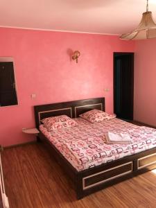 a bedroom with a bed with a pink wall at Silviu in Baile Unu Mai +9 photos