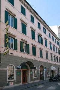 un grand bâtiment rose avec volets verts dans une rue dans l'établissement Hotel Italia, à Trieste