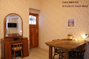 a room with a wooden table and a mirror at カフェロッジ Touch Wood in Biei