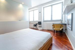 Schlafzimmer mit einem Bett, einem Schreibtisch und Fenstern in der Unterkunft EASY CENTRAL LOFT - MONZA in Monza