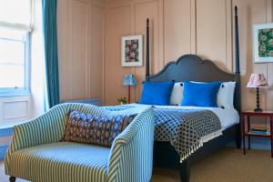 1 dormitorio con 1 cama con silla y sofá en The Mitre, Hampton Court en Kingston upon Thames