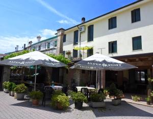 twee parasols en tafels en stoelen voor een gebouw bij osteria canal 1803 in Borso del Grappa