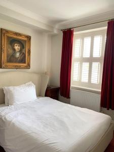 a bedroom with a white bed with a painting on the wall at The Old Manor House Hotel in Keynsham
