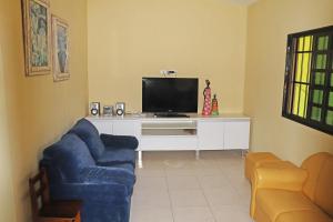a living room with a blue chair and a tv at Casa Verde in Porto De Galinhas