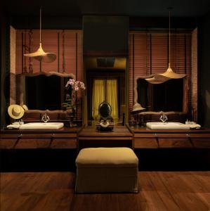 a bathroom with two sinks with mirrors and a stool at Chandra Residence in Chiang Mai
