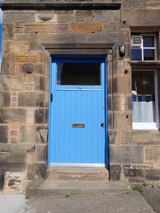 una puerta azul en el lateral de un edificio de piedra en The Store, harbour holiday cottage, en Port Seton