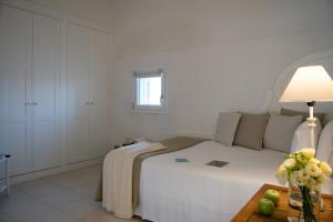 a white bedroom with a large bed and a table at La Peschiera in Monopoli