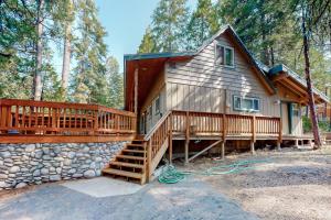 a home with a large deck and a stone wall at Williams Cabin in Shaver Lake