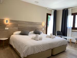 a bedroom with a large white bed with two pillows at Hotel El Cobertizo in Plasencia del Monte