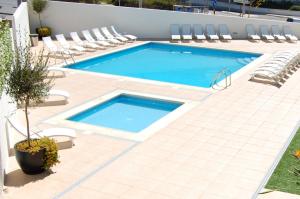 uma piscina com cadeiras e uma piscina em Apartamentos Mare em Nazaré