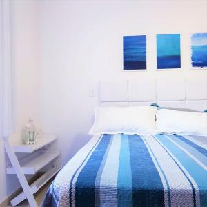 a bedroom with a bed with a blue and white blanket at Paraiso no Guarujá Enseada - Piscina - Ar Condicionado - WIFI - Garagem in Guarujá