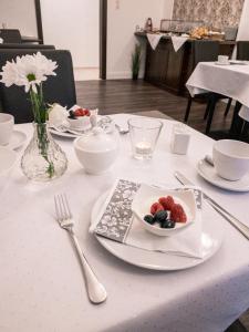 a white table with a plate of fruit on it at Pension Villa Pangea in Bad Lauterberg