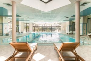 a large swimming pool with two chairs in a building at Domaine Les Sources de Dieulefit in Dieulefit