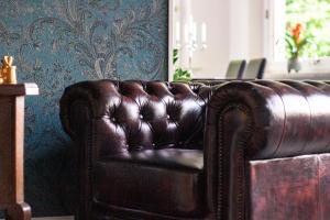a brown leather couch in a room with a wall at Pension Villa Pangea in Bad Lauterberg