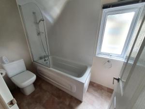 a white bathroom with a shower and a toilet at Sea Shore Lodge Mudeford in Christchurch +16 photos