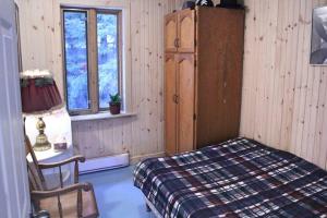 a bedroom with a bed and a lamp and a chair at La maison du capitaine in Tadoussac