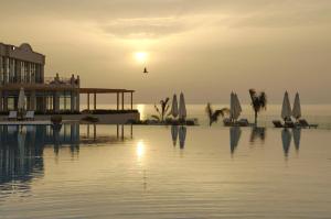 a pool of water with a sunset in the background at Cleopatra Luxury Resort Sharm El Sheikh in Sharm El Sheikh