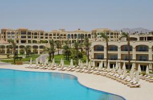 a resort with a swimming pool with lounge chairs and umbrellas at Cleopatra Luxury Resort Sharm El Sheikh in Sharm El Sheikh