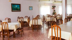 uma sala de jantar com mesas brancas e cadeiras de madeira em Los Dos Alemanes em Melide