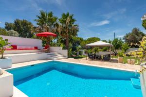 a pool with a patio and a table and umbrella at Villa AL Fresco in Guia