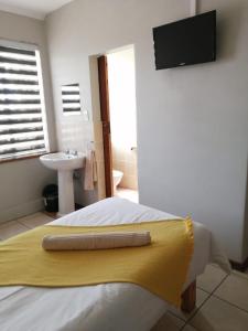 a bedroom with a bed with a yellow towel on it at Acorn Lodge & SKYDECK in Potchefstroom