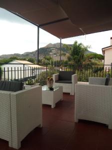 a patio with white chairs and tables and an umbrella at Appartamento a Mondello in Mondello