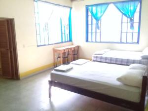 two beds in a room with two windows at Hostal Juan Lindo in San Pedro Sula