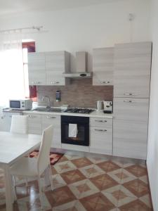 una cucina con armadi bianchi, tavolo e piano cottura di Appartamento a Mondello a Mondello