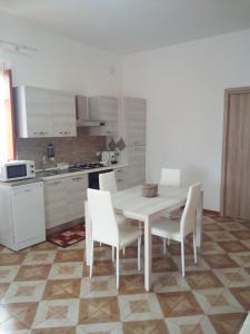 a white kitchen with a white table and chairs at Appartamento a Mondello in Mondello