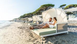 Un uomo e una donna seduti su un letto sulla spiaggia di The Sense Experience Resort a Follonica