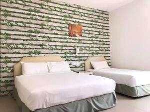 duas camas num quarto com uma parede de tijolos em Summer Green Lodge em Kuantan