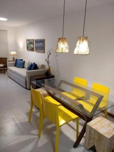 a living room with a glass table and yellow chairs at Village Angelim in Itacaré