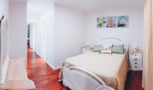 a bedroom with a white bed and a wooden floor at Dorisol Vista Formosa by rentallido in Funchal
