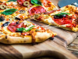 dos rebanadas de pizza en una tabla de cortar de madera en The Oakhill Inn, en Shepton Mallet