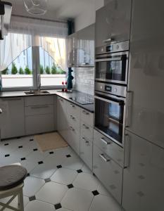 a kitchen with stainless steel appliances and white cabinets at Polana in Nowy Targ