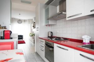 kuchnia z białymi szafkami i czerwonymi blatami w obiekcie YouHosty - Delle Genziane 7 w Mediolanie