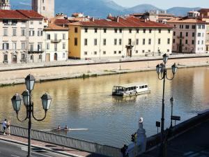 una barca in un fiume in una città con edifici di Vacanze Pisane a Pisa