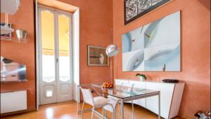 a dining room with orange walls and a glass table and chairs at Terrazza Torno in Torno