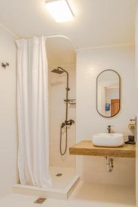 a bathroom with a shower curtain and a sink at Αlissachne Suites in Limnionas