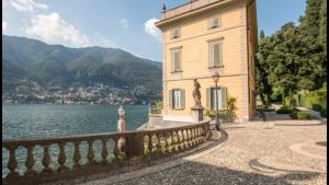 a building with a fence next to a body of water at Terrazza Torno in Torno