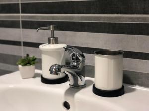 um lavatório de casa de banho com uma torneira e uma chávena em Apartman Spring em Sombor