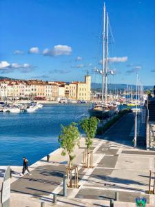 a man walking down a sidewalk next to a marina at Accostage Vieux-Port - Appartements & Parking en option in La Ciotat