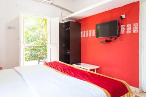 a red bedroom with a bed and a tv on a wall at Oceanic Pearl Beach Guest House in Calangute