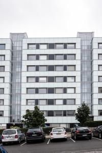 un grand bâtiment blanc avec des voitures garées dans un parking dans l'établissement Tuure´s studio near to Art Museum, à Turku