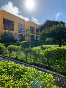 a yellow building with bushes in front of it at Flat em Serra Negra - PE - Condomínio Próximo Bodega de Véio, shows e eventos in Bezerros