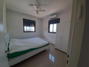 a bedroom with a bed and a ceiling fan at Family apart in Nahariyya